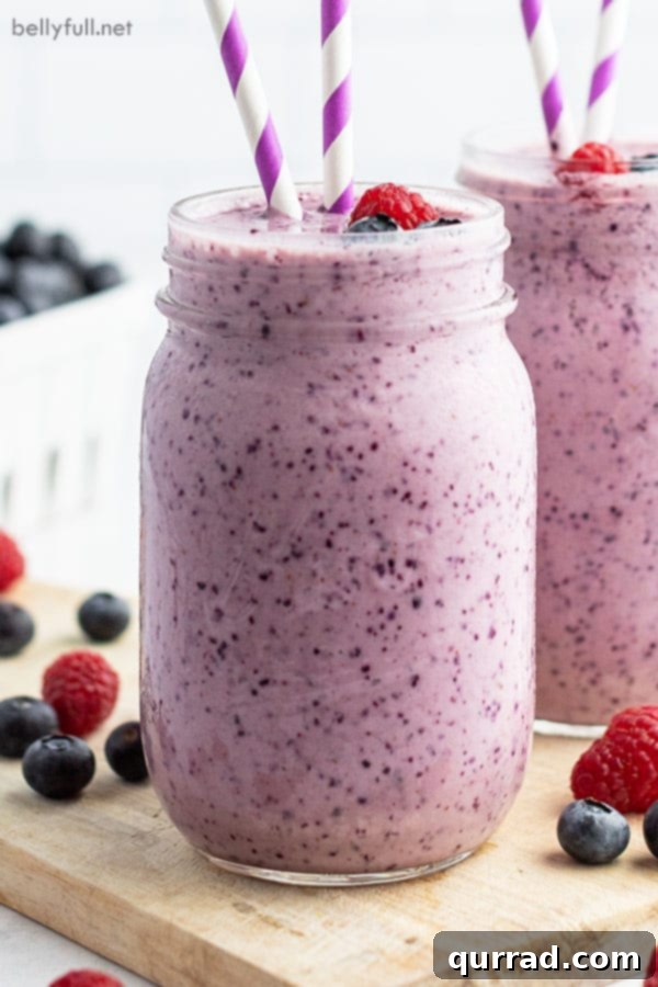 A close-up shot of a creamy blueberry smoothie served in a rustic glass jar, emphasizing its smooth texture and appealing color.