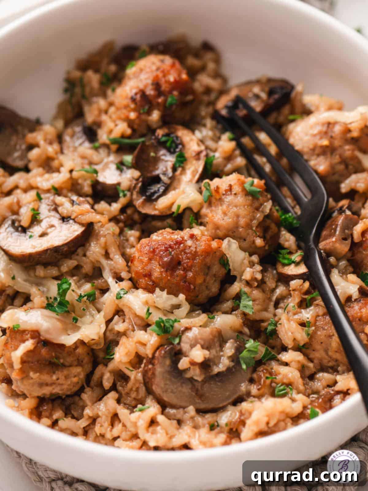 A close-up of a bowl of French onion meatballs and rice, garnished with parsley, ready to be eaten