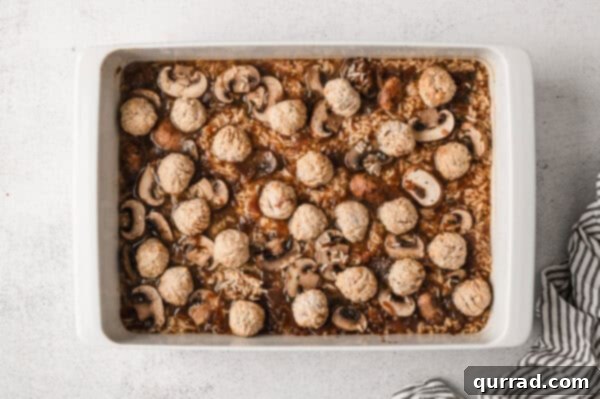 Frozen meatballs placed on top of French onion rice in a casserole dish