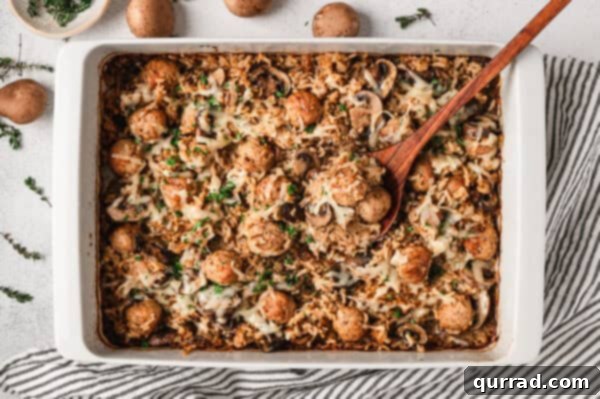Overhead view of a baking dish of French onion meatballs and rice, garnished with parsley