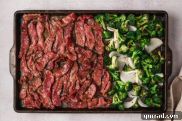 Effortless Sheet Pan Beef and Broccoli 5 Slices of marinated steak on a baking sheet next to roasted broccoli and onions.