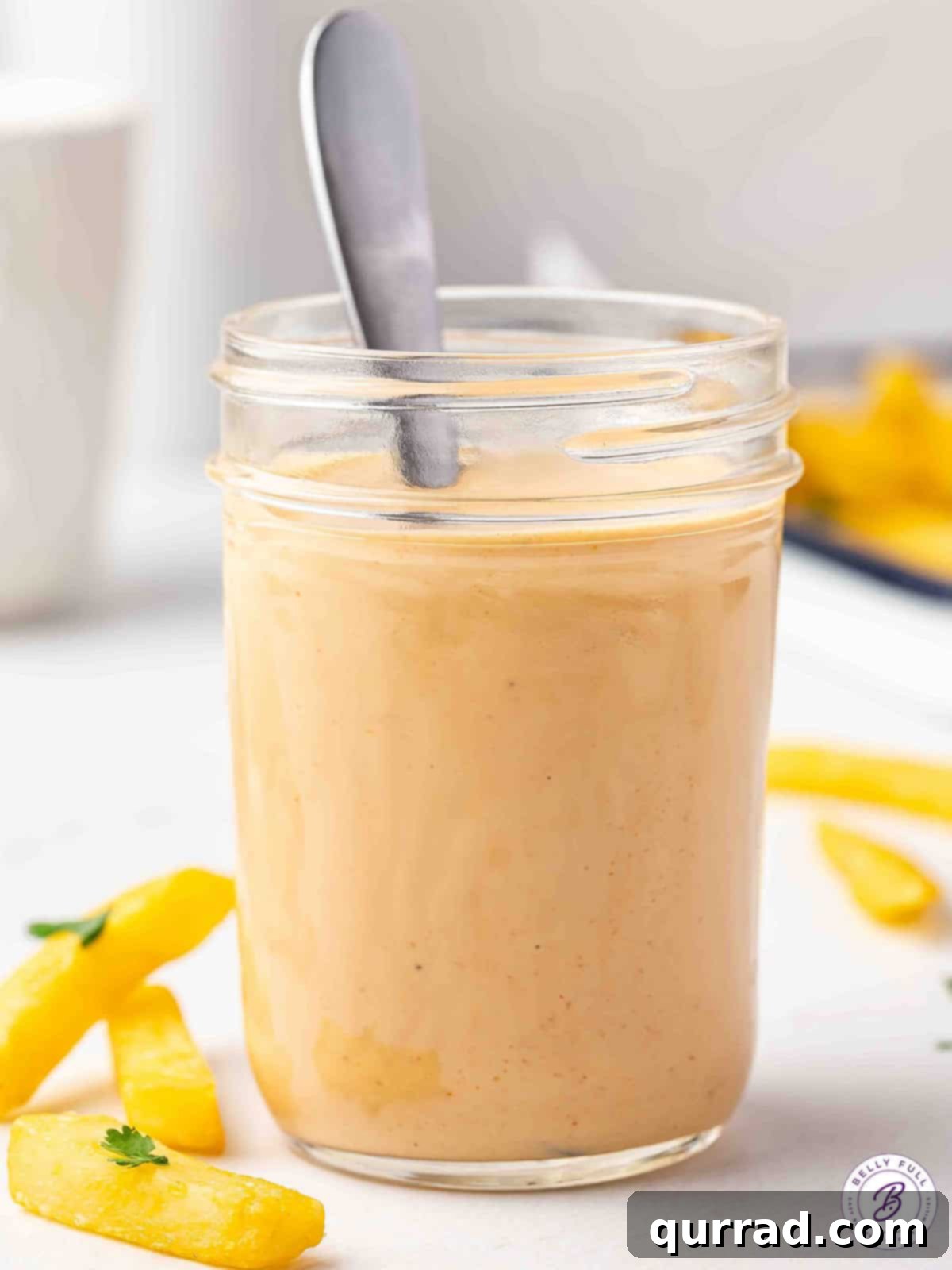 The Encore Sauce 7 A close-up shot of a spoon in a clear glass jar filled with rich, creamy comeback sauce.