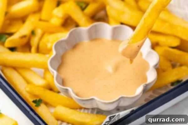 The Encore Sauce 5 A crispy French fry being dipped into a small bowl of creamy comeback sauce.