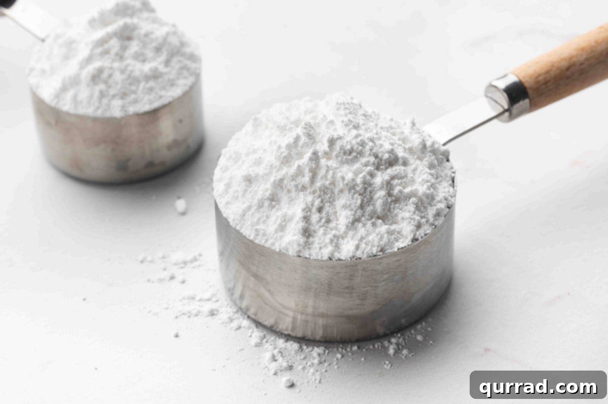 Measuring cup overflowing with homemade powdered sugar.