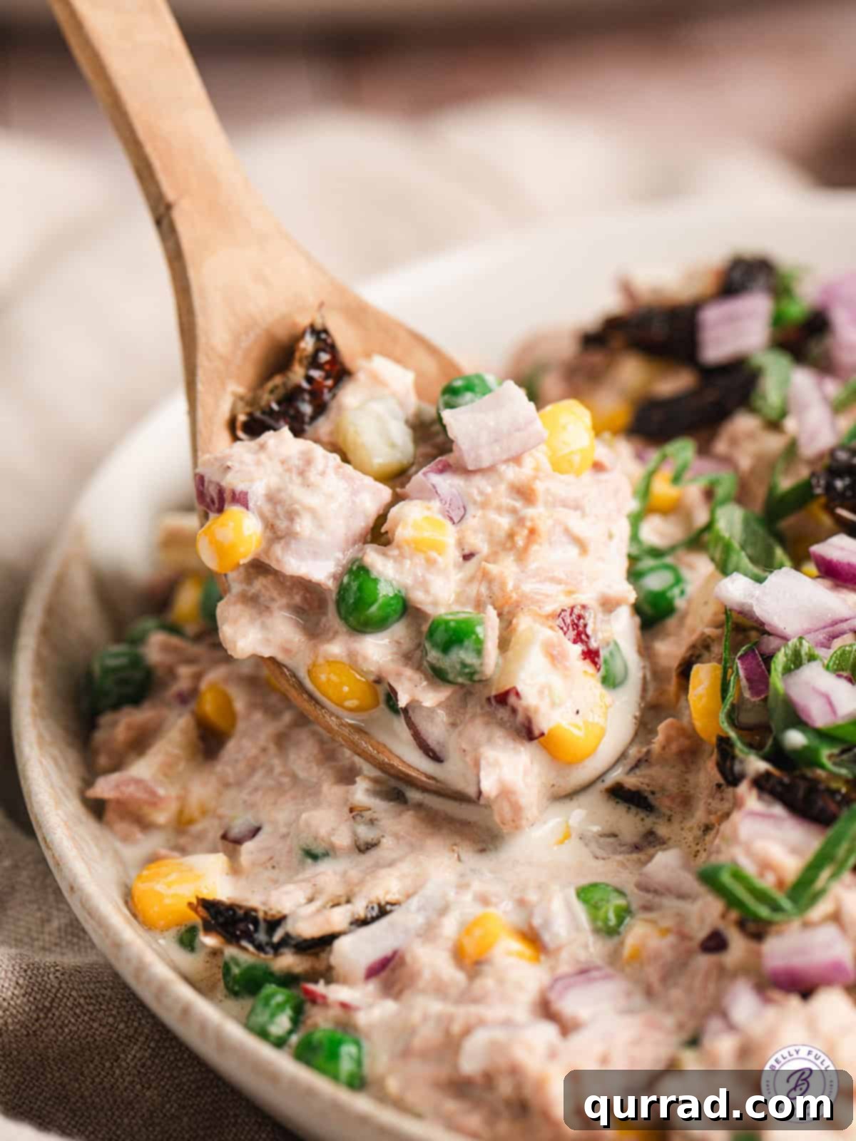 Matthew McConaughey's Tuna Salad combines your classic tuna salad ingredients with a handful of sweet, spicy, and crunchy ingredients, offering a bold and refreshing twist. A wooden spoon in Matthew McConaughey's tuna salad
