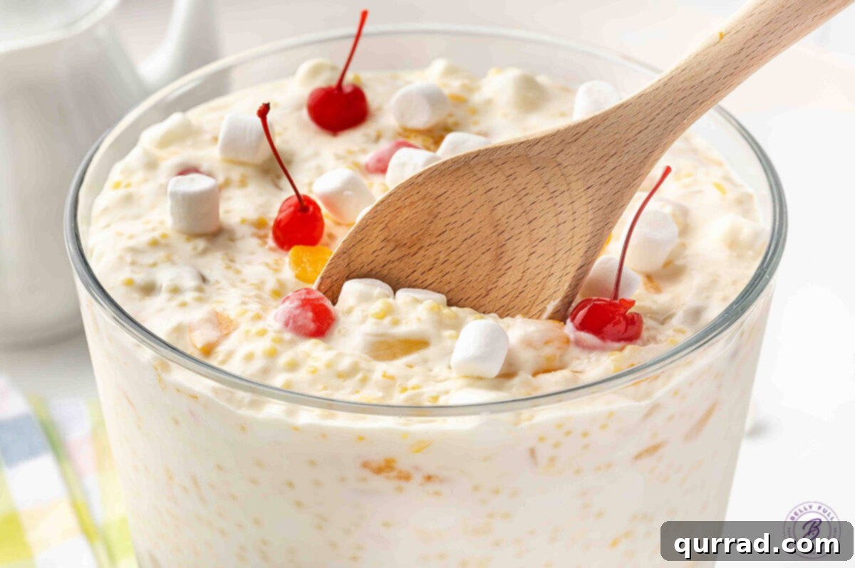 A wooden spoon resting in a bowl of creamy Frog Eye Salad.