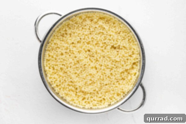 Acini di pepe pasta cooking in a pot of water.