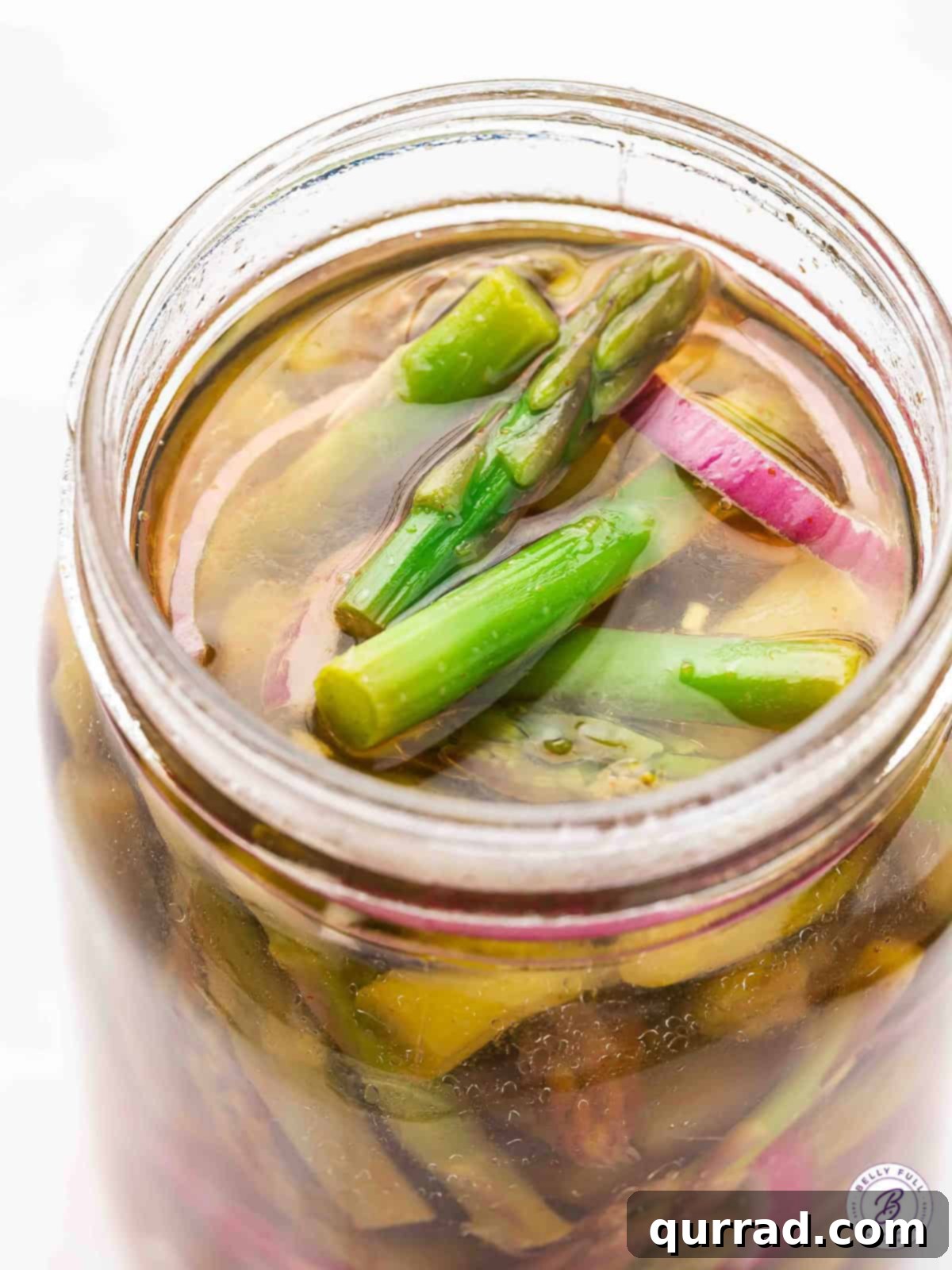 Fresh asparagus and onion are quick-pickled in a tangy and slightly spicy mixture in this Pickled Asparagus recipe. Overhead view of a jar of pickled asparagus