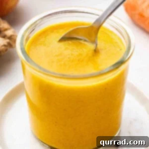 A spoon in a glass jar of Carrot-Ginger dressing