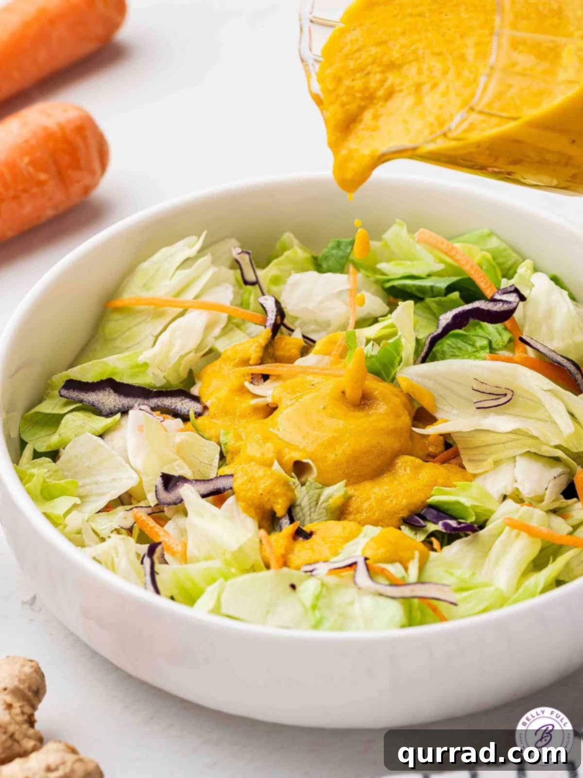Freshly Made Carrot-Ginger Dressing - Perfect for Drizzling and Enhancing Your Meals Drizzling homemade carrot-ginger dressing over a fresh, vibrant green salad
