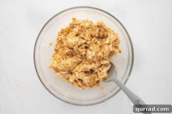 A rich mixture of shredded chicken, softened cream cheese, shredded Mexican cheese, and taco seasoning, perfectly combined in a bowl for taco filling.