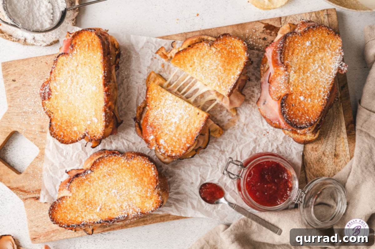 Overhead view of Monte Cristo grilled cheese sandwiches, one pulled apart to show the melted cheese and layers between the halves