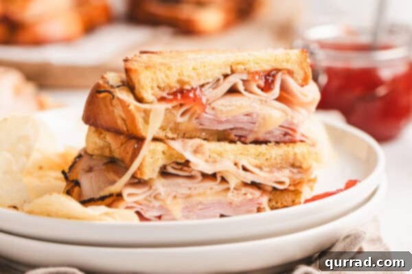 Two halves of a Monte Cristo grilled cheese stacked on a white plate, ready to be served