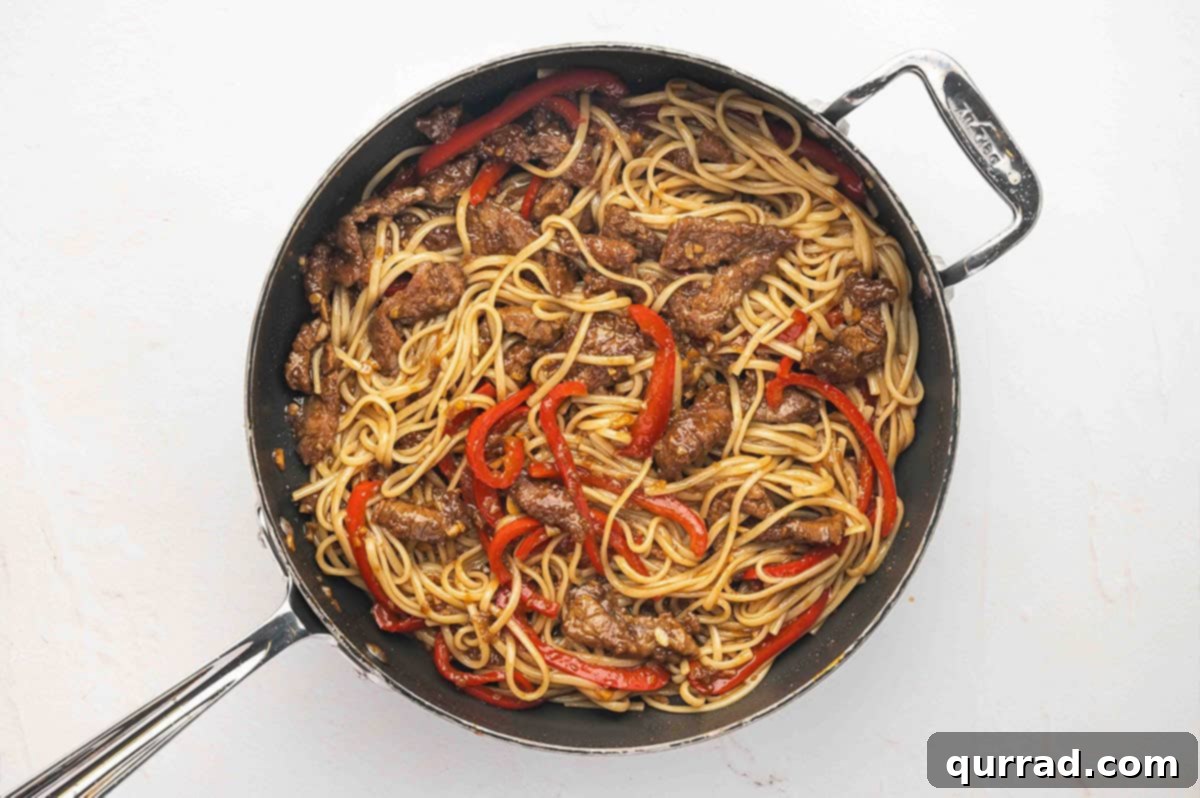 Overhead view of a skillet of Mongolian beef noodles, with all ingredients combined