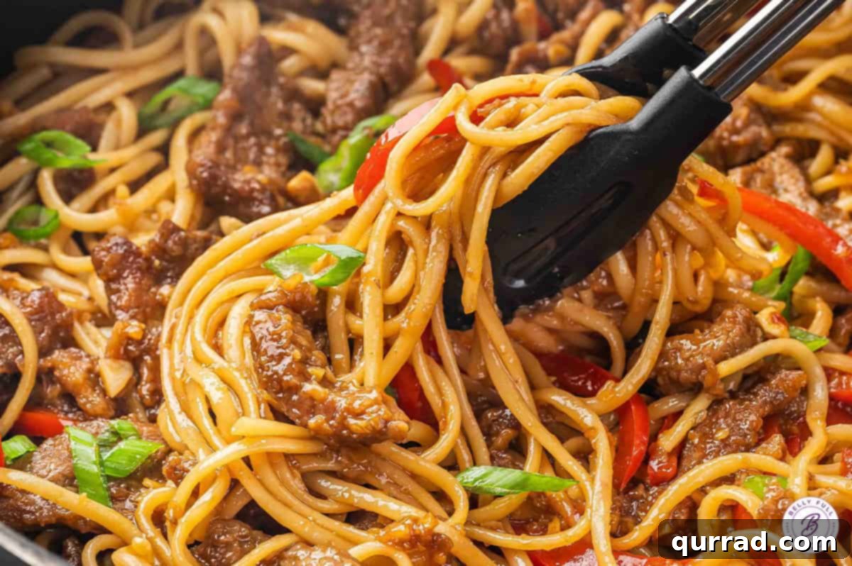 Tongs serving Mongolian beef noodles from a skillet into a bowl