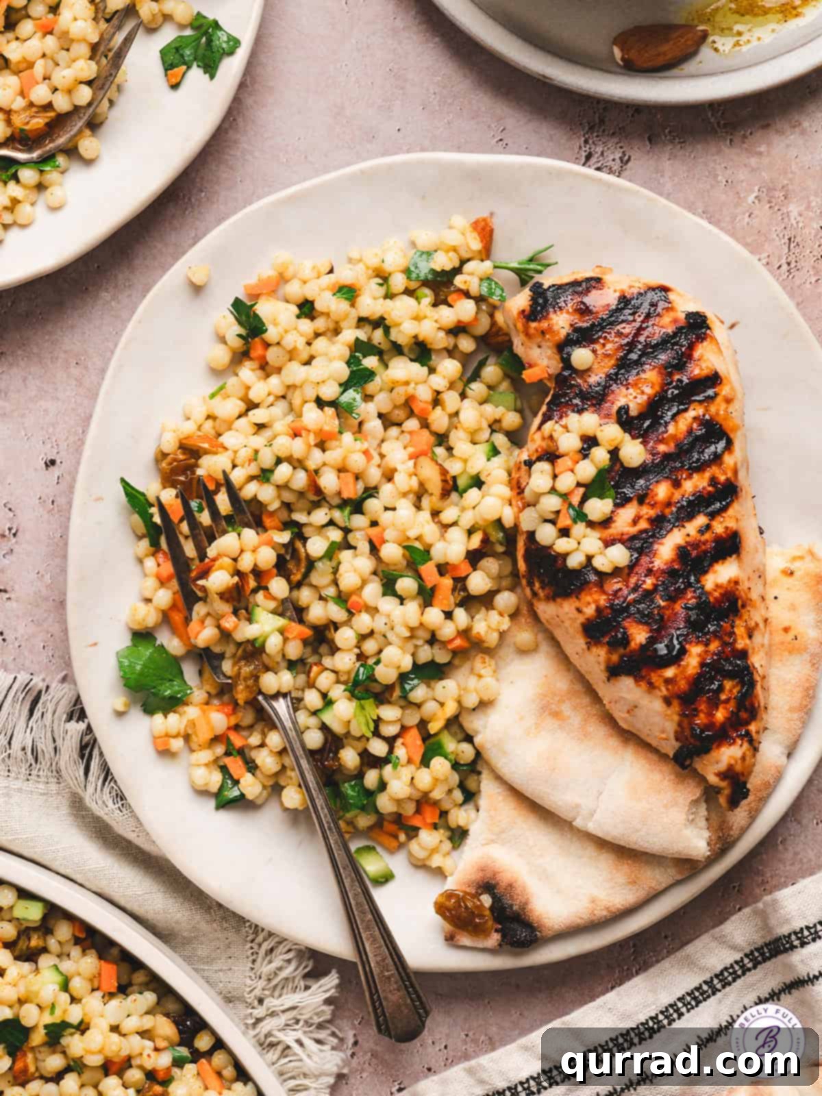 Curried couscous salad on a white plate with grilled chicken