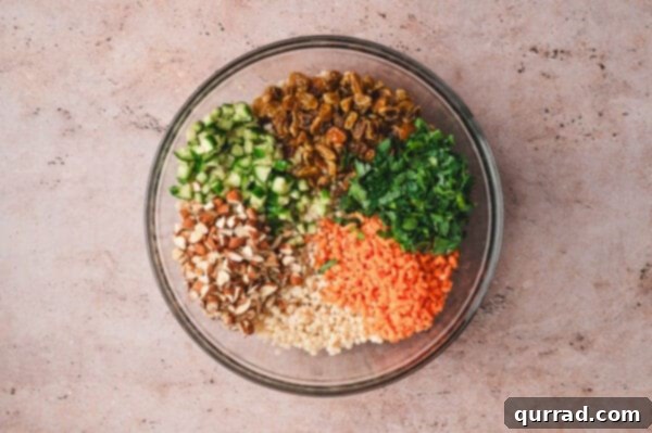 Golden raisins, parsley, carrots, almonds, and cucumbers in a bowl with couscous