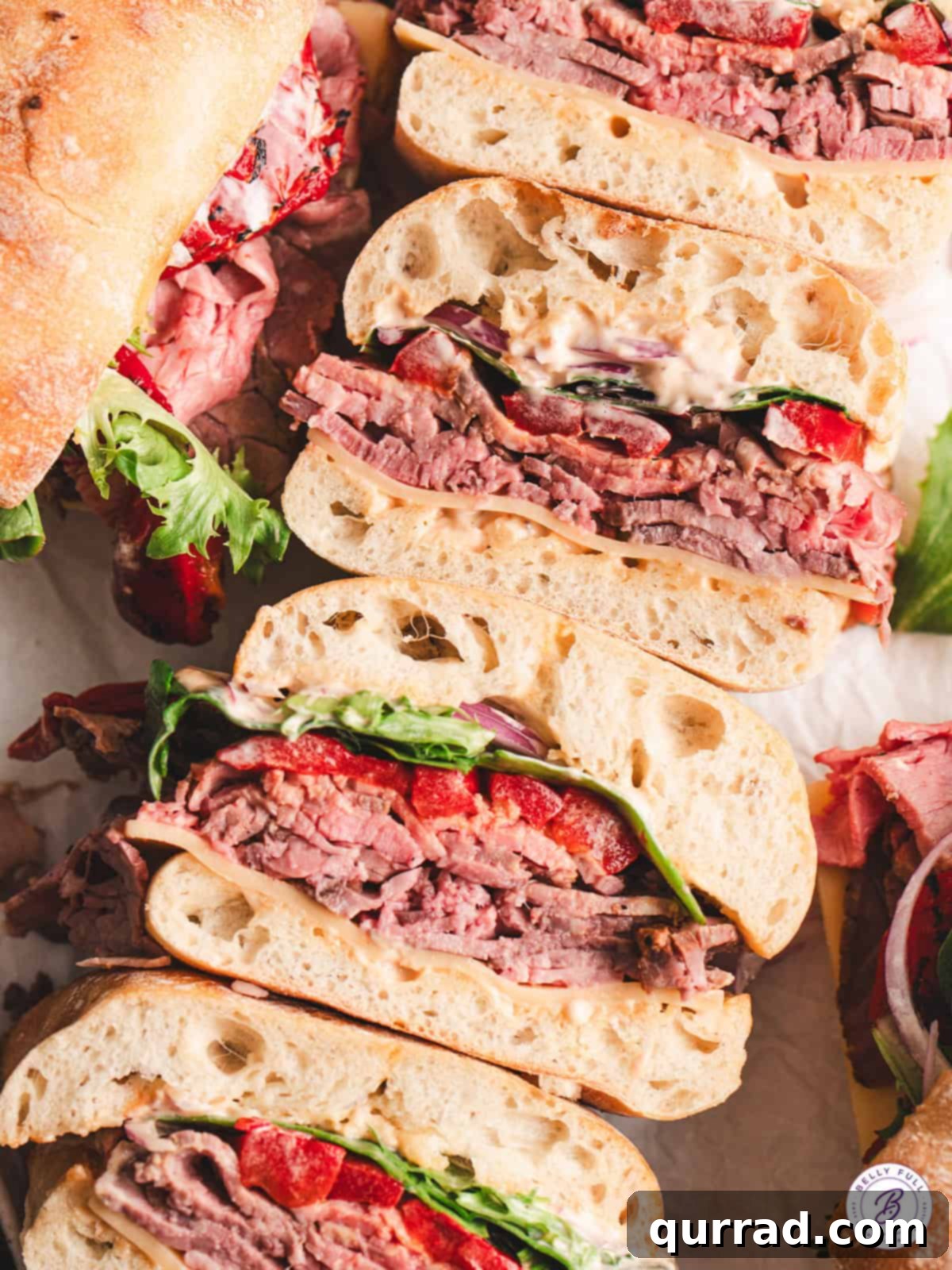 The hearty and satisfying El Matador Sandwich, showcasing its rich fillings. El Matador sandwich cut in half, stacked to show all the delicious layers of meat, cheese, peppers, and greens.