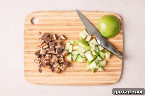 Diced Snickers and diced apples on a cutting board