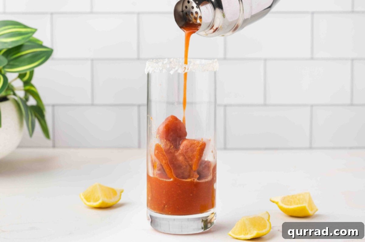These fun Bloody Mary Ice Cubes are the secret to keeping a Bloody Mary cocktail chilled and full of flavor. No watered down cocktails here! Pouring Bloody Mary mix over Bloody Mary ice cubes