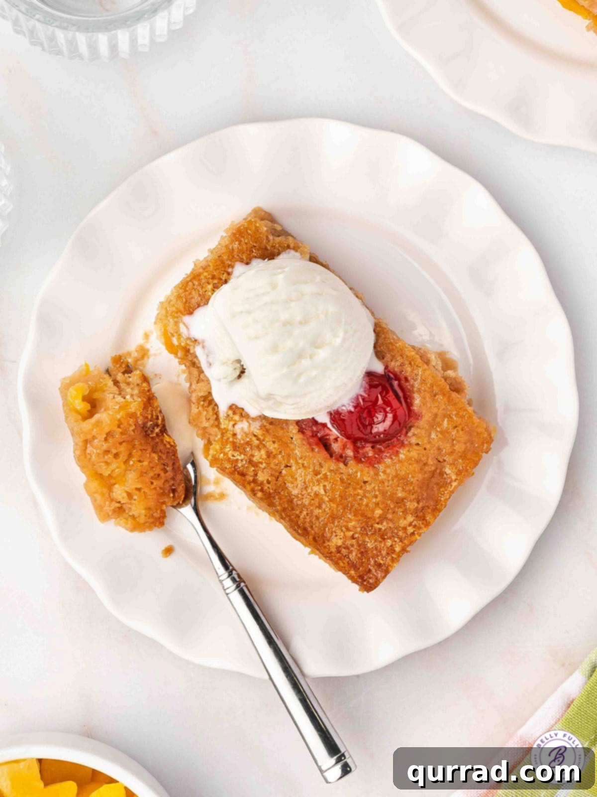Cuppa Cake Delight 10 A slice of warm Cuppa Cuppa Cake topped with a scoop of melting vanilla ice cream on a white plate, ready to be enjoyed.