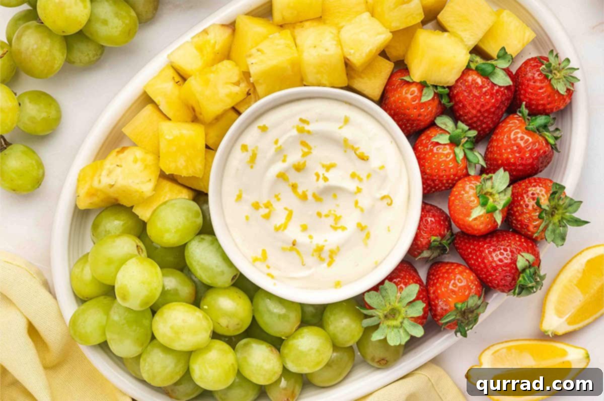 Zesty Lemonade Fruit Dip 6 An overhead view of a beautifully arranged fruit platter featuring a central bowl of lemonade fruit dip, surrounded by an assortment of fresh fruits.