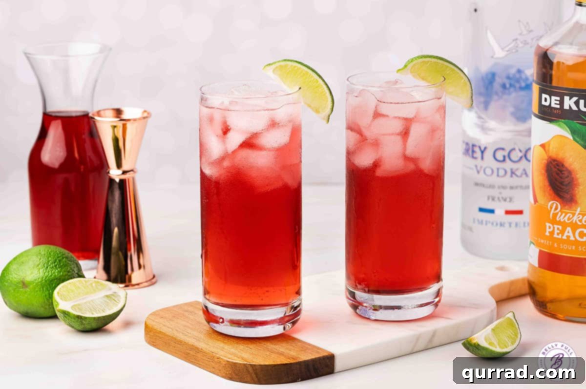 Two vibrant Woo Woo cocktails, garnished with lime wedges, clinking glasses in a celebratory toast.