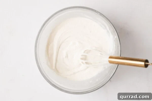 Whisking mayonnaise, sour cream, and vinegar for the dressing