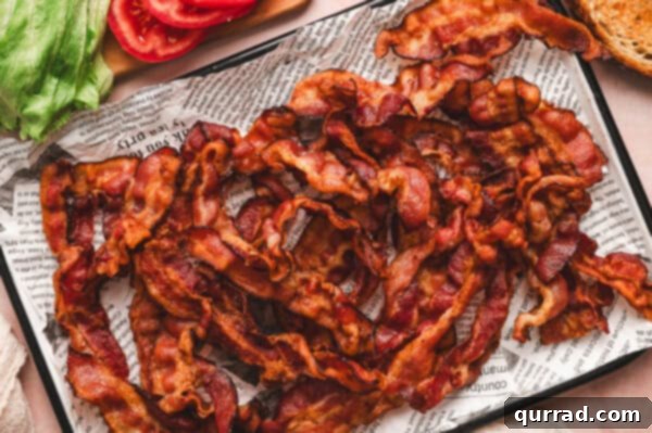 Crispy air fryer bacon resting on a baking sheet lined with paper towels.