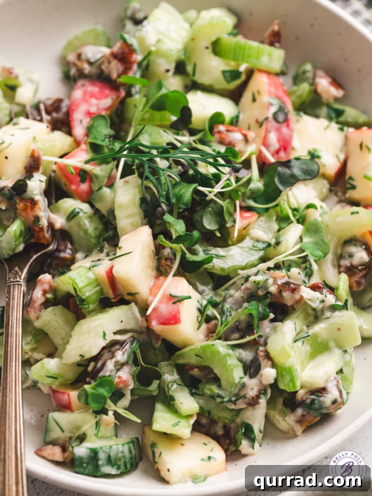 A close-up of a bowl filled with Apple Date Celery Salad, showing the detailed texture of the creamy dressing and the chopped ingredients, ready to be served.