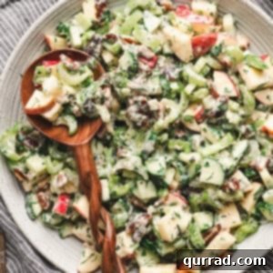 A wooden spoon in a bowl of apple date celery salad
