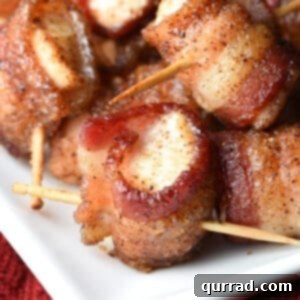 Close-up of a single bacon wrapped chicken bite with perfectly crisp bacon and a golden glaze.