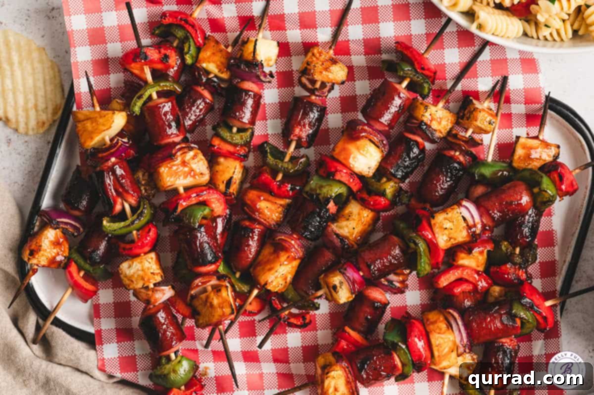 Make your summer gatherings unforgettable with these kid-approved Grilled Hot Dog Kabobs – a delightful combination of savory hot dogs, colorful veggies, and tropical pineapple, all grilled to perfection. Grilled hot dog kabobs arranged artfully on a checkered picnic blanket, ready for an outdoor feast.