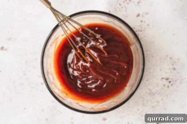 Sizzling Skewer Dogs 5 Ingredients for the savory BBQ glaze being whisked together in a bowl.