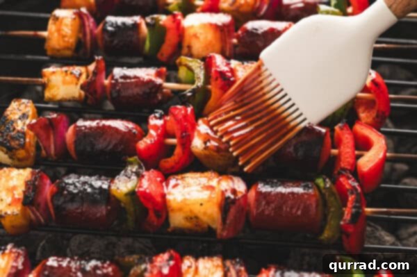 Sizzling Skewer Dogs 6 Hot dog and vegetable kabobs being brushed with BBQ sauce on a hot grill.
