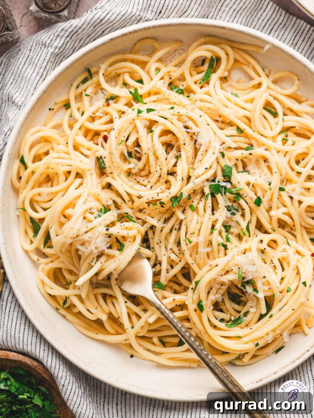 Pasta tossed with olive oil, garlic, and parmesan cheese for a simple and delicious Spaghetti Aglio e Olio recipe, ready in just 25 minutes! Overhead view of a plate of spaghetti aglio e olio, garnished with fresh parsley and Parmesan cheese