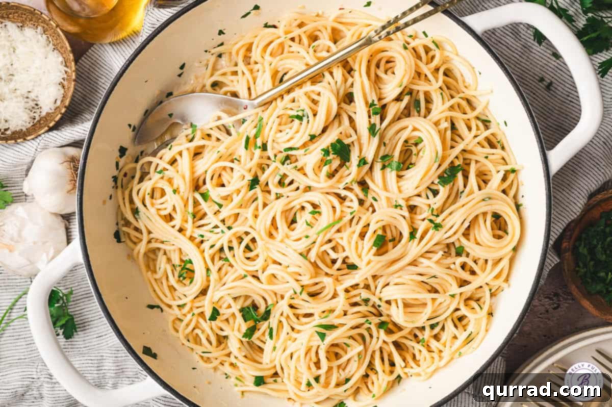 Garlic and Olive Oil Spaghetti 6 A serving spoon lifting a portion of Spaghetti Aglio e Olio from a pan, showing the glossy pasta