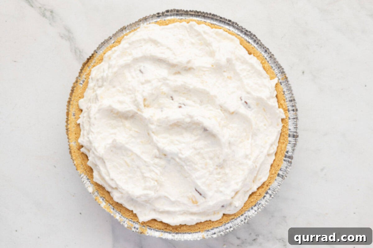 Prepared Million Dollar Pie filling spread evenly inside a graham cracker crust.