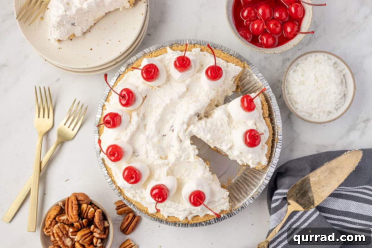 Overhead view of Million Dollar Pie with a slice removed, surrounded by bowls of cherries, coconut, pecans, and gold forks.