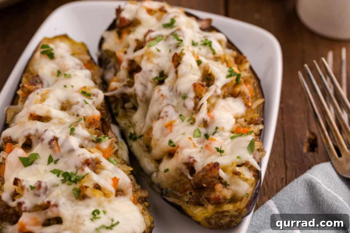 Savory Stuffed Eggplant 12 Close-up of stuffed eggplant served with a fork and knife on a white plate, garnished with parsley.