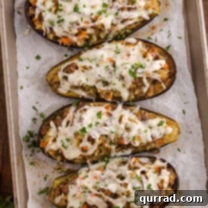 Savory Stuffed Eggplant 3 Baked stuffed eggplant halves filled with a golden breadcrumb and vegetable mixture, garnished with fresh parsley on a white plate.