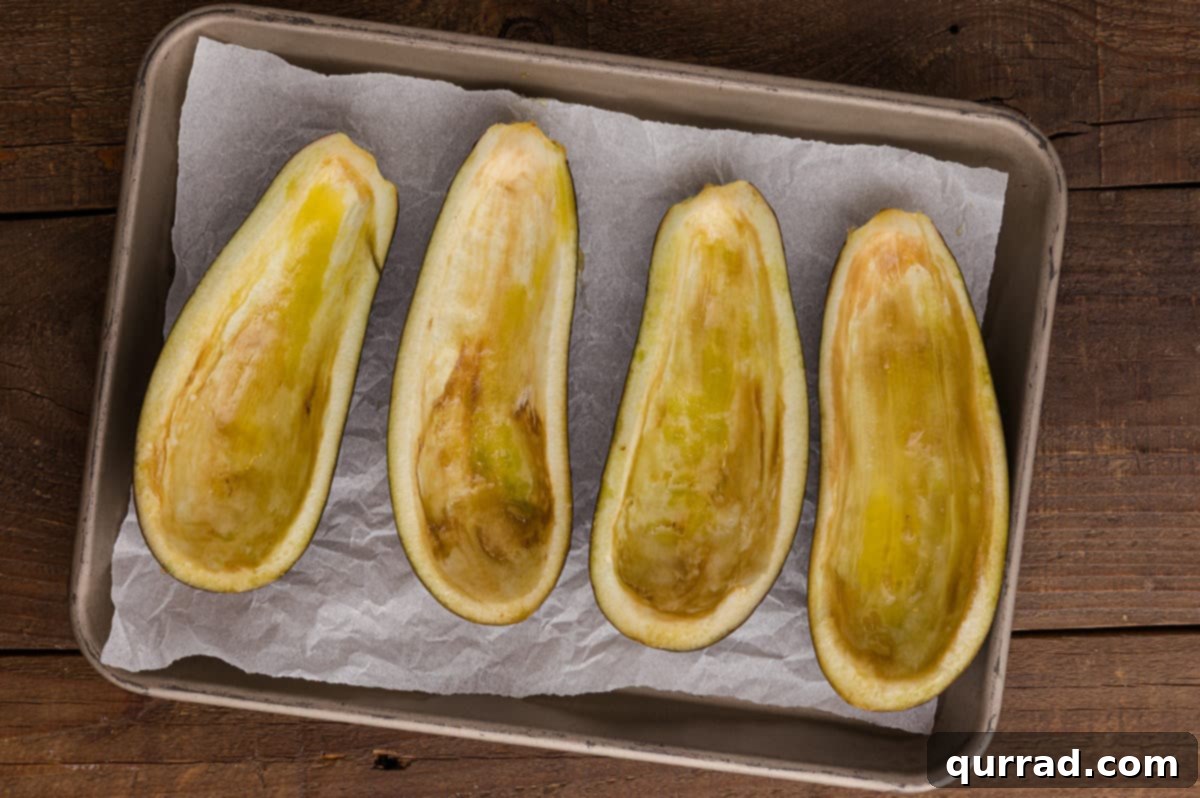 Savory Stuffed Eggplant 5 Two halved eggplants on a cutting board with the flesh scored in a crisscross pattern.