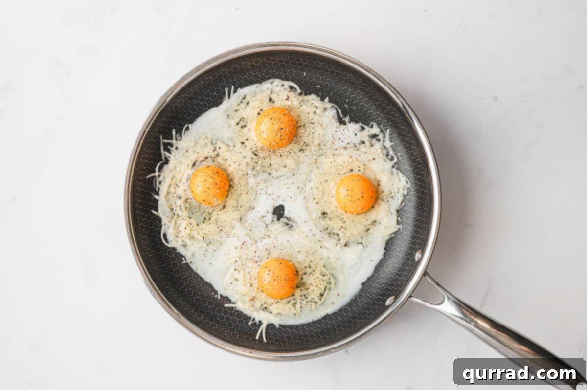 Crispy Cheese Eggs 5 Cooked cheese nests in a skillet with an indentation in the center, ready for eggs.