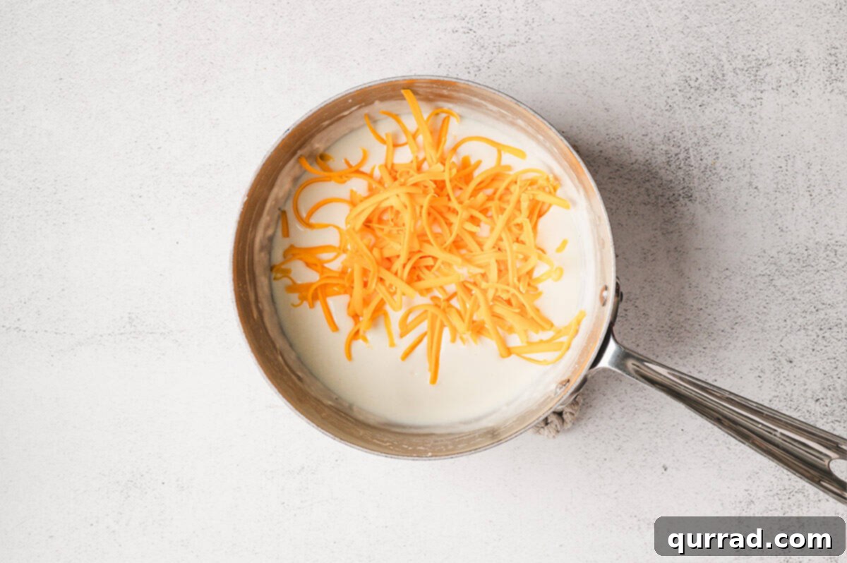 Liquid Gold Cheese 7 Shredded sharp cheddar cheese added to the thickened milk mixture.