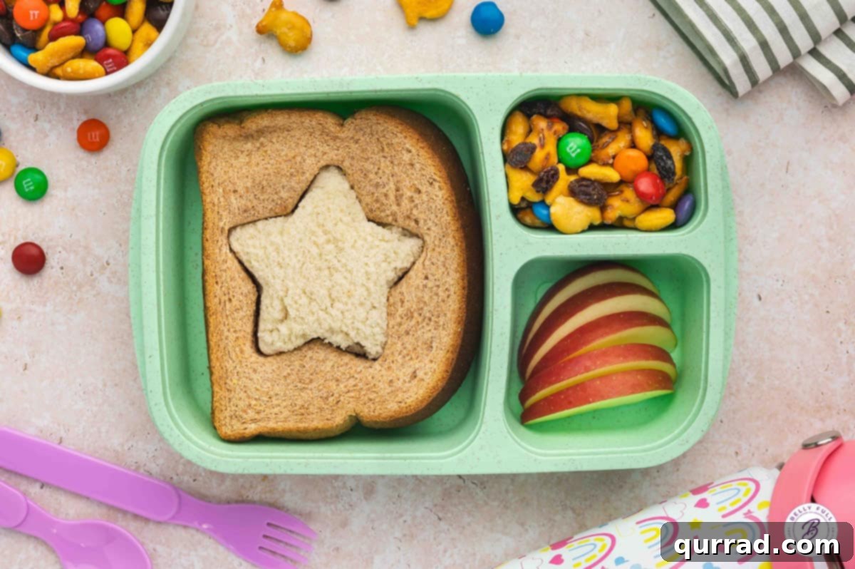 Delicious & Easy School Lunches 3 Inside out white-wheat star sandwich, sliced apples, and trail mix in a colorful bento box for a fun school lunch.