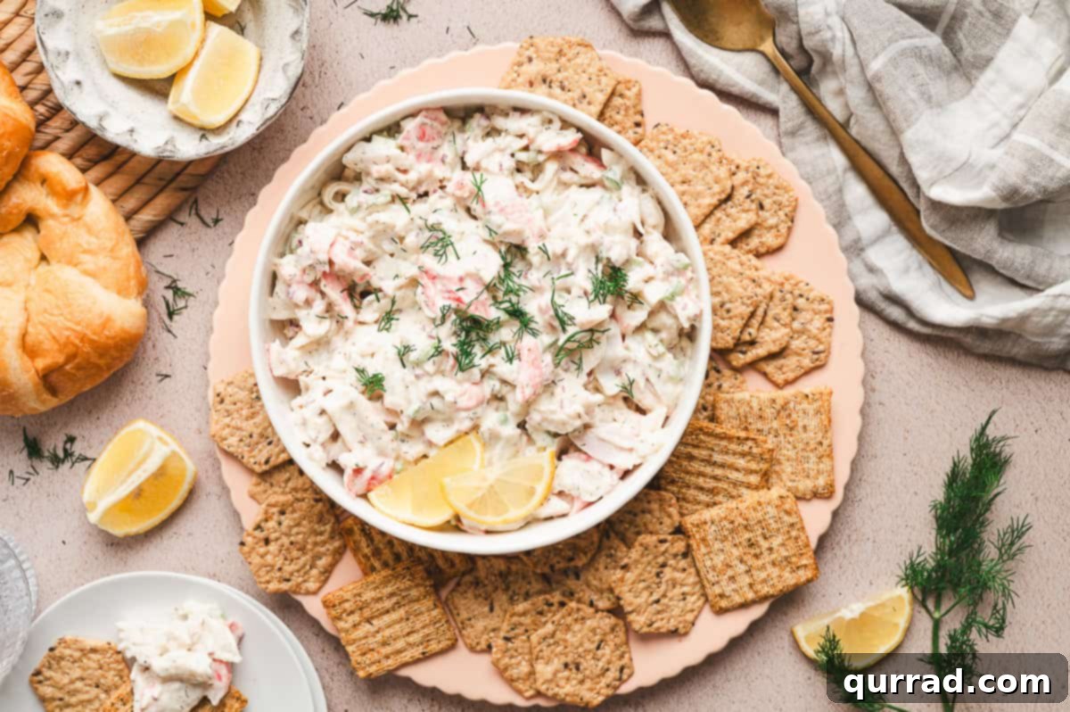 Signature Crab Salad 8 Overhead view of a finished crab salad dish, garnished with fresh dill, surrounded by an assortment of crackers.