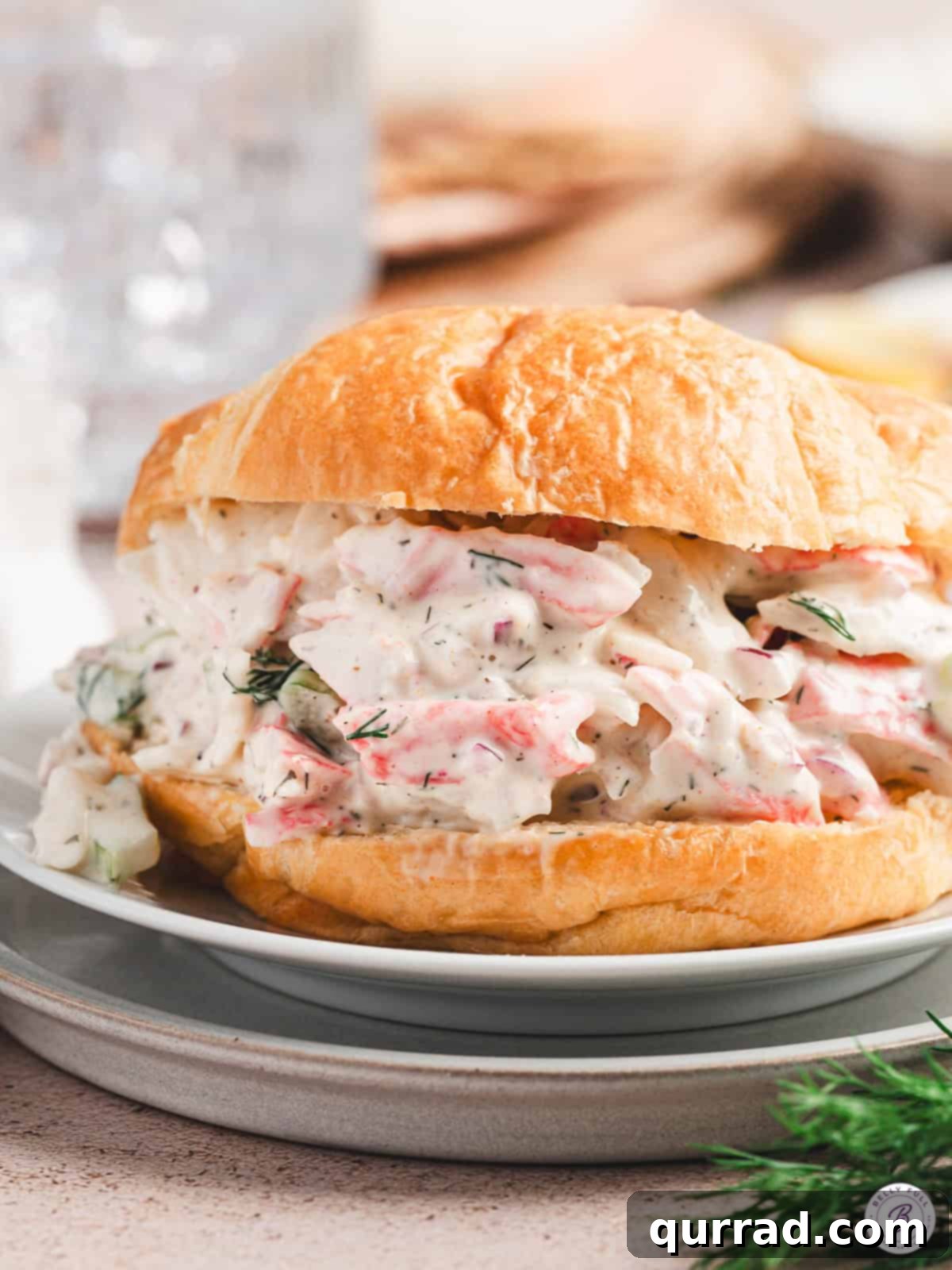Signature Crab Salad 9 A perfectly assembled crab salad sandwich on a white plate, ready to be enjoyed.