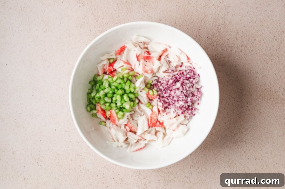 Signature Crab Salad 5 Imitation flaked crab meat, finely diced celery, and red onion combined in a mixing bowl.