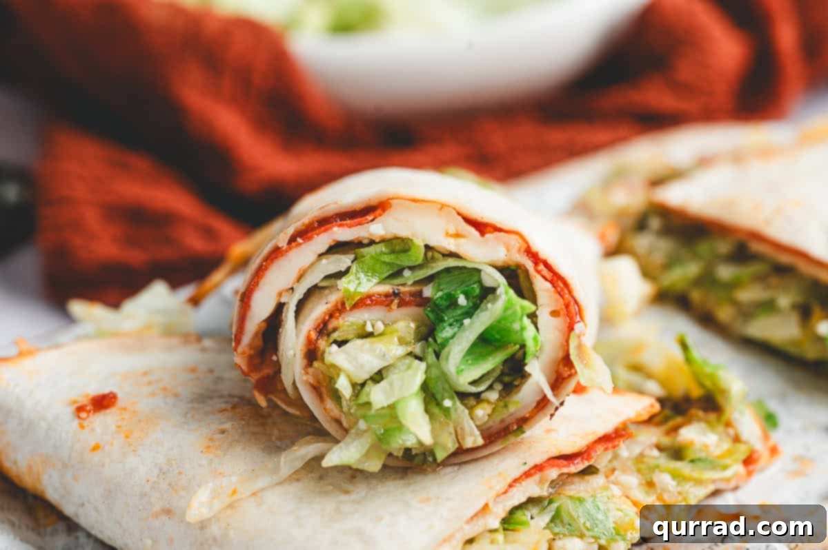 Pizza Garden Wrap 9 Rolled pizza salad wrap sliced to show layers of melted cheese, pepperoni, and lettuce filling.