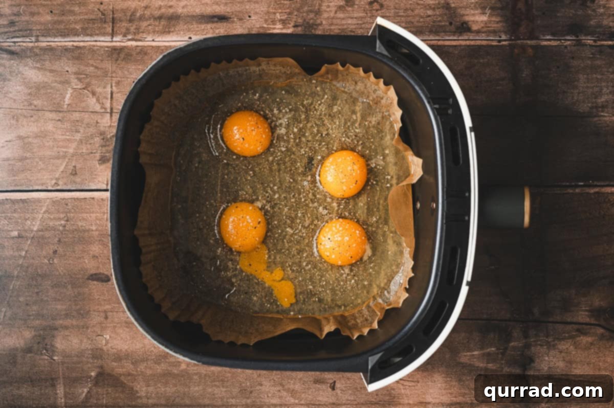Fluffy Air Fryer Egg Frittata 4 Four raw eggs cracked directly into the air fryer basket on top of the parchment liner, seasoned lightly with salt and pepper.